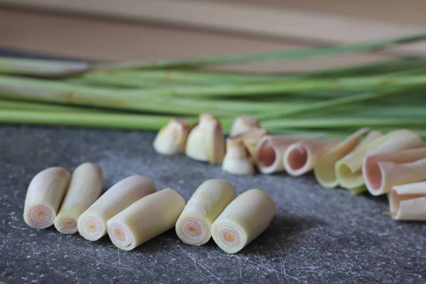 slicing lemongrass on a grey cutting board