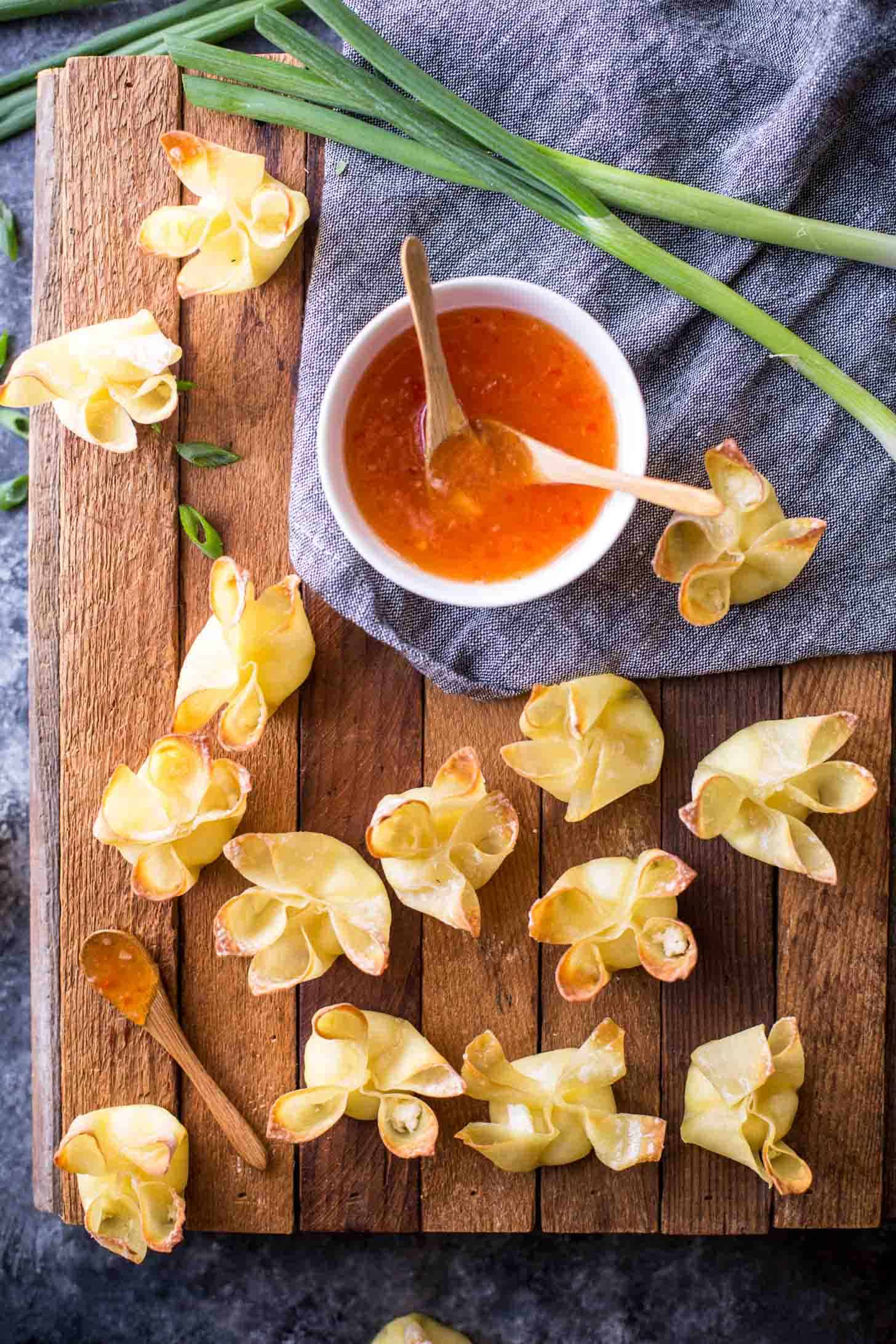 overhead image of crab rangoon and sauce on a wooden tray