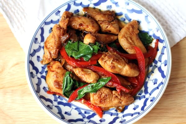 overhead image of chicken with peppers and basil in a blue and white bowl