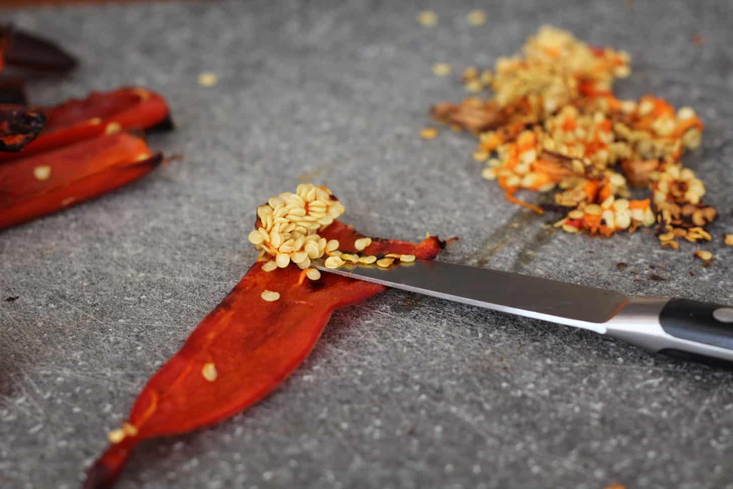 removing seeds from sliced red chili pepper