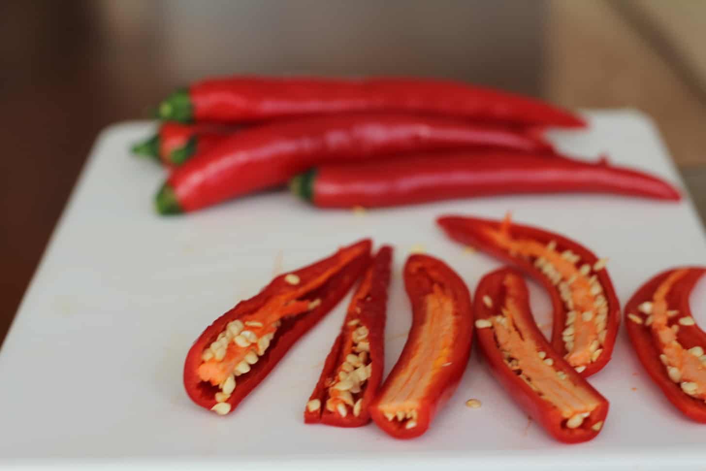 sliced red chili peppers on a white cutting board