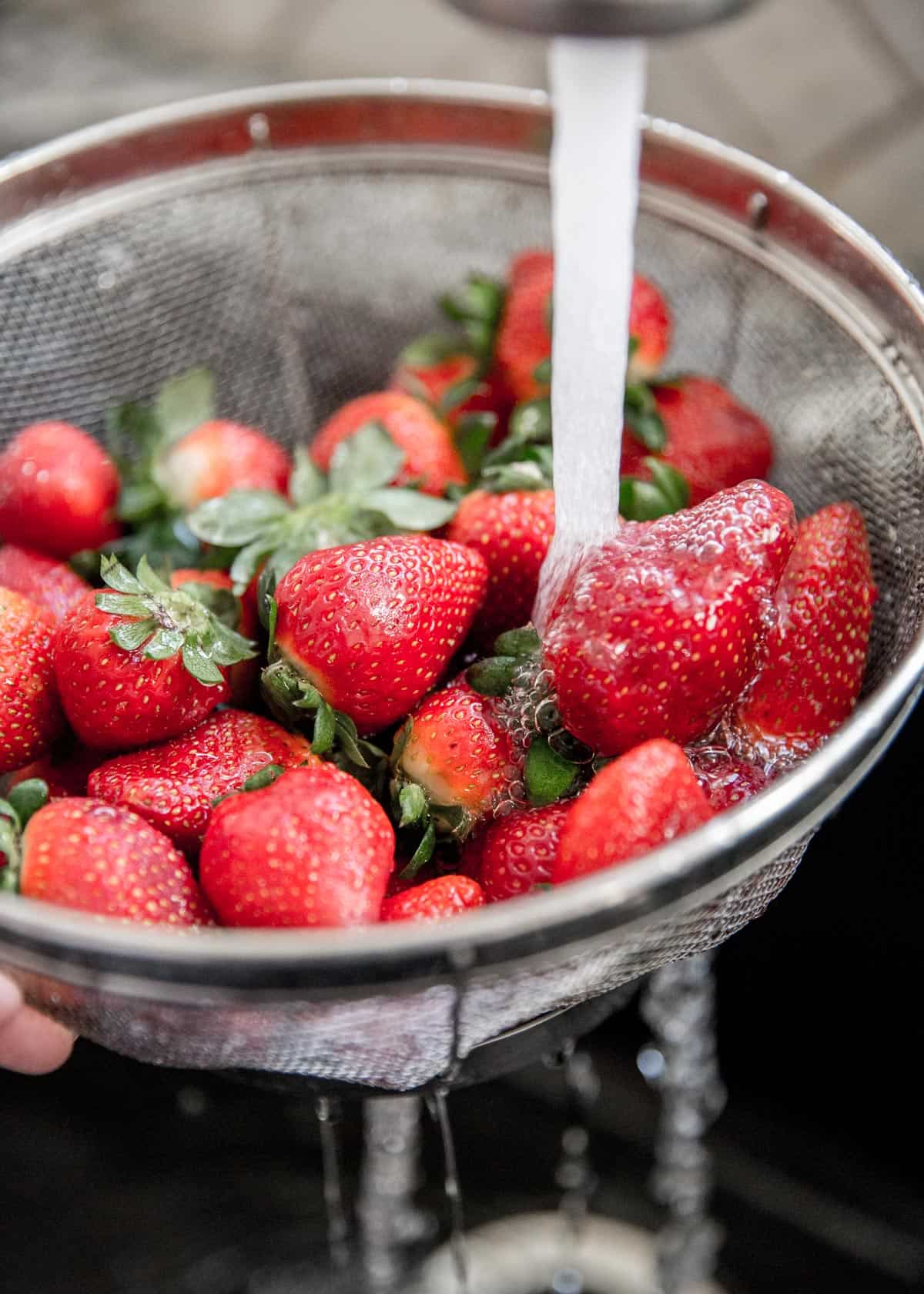 rinsing strawberries in a strainer