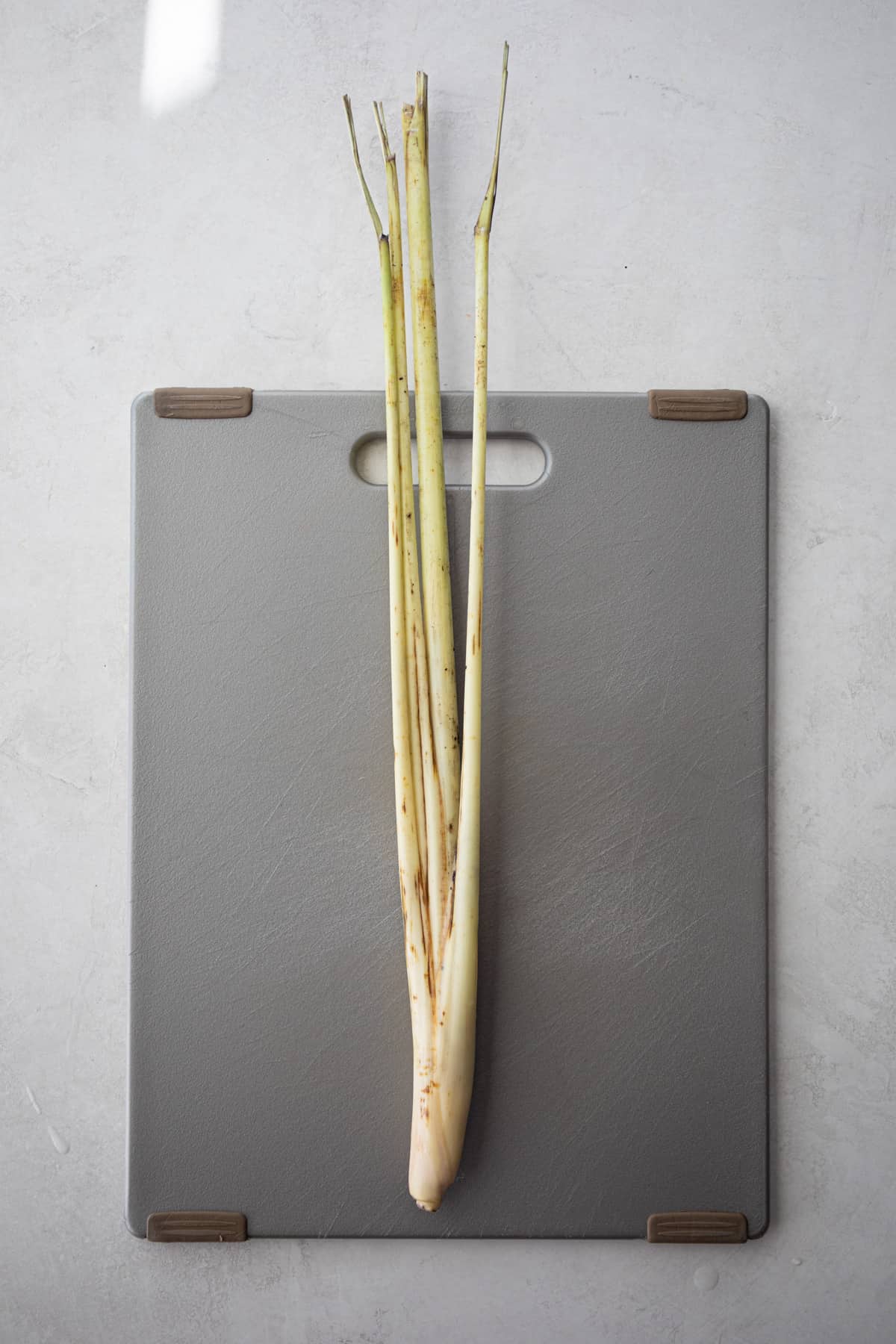 overhead image of lemongrass on a grey cutting board