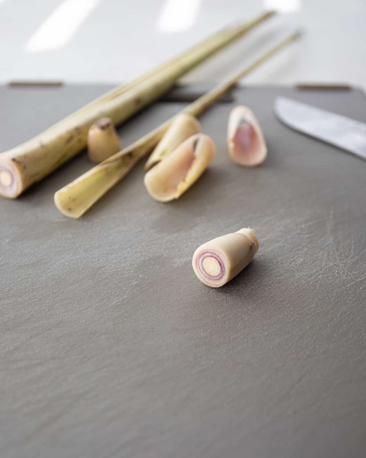 cutting lemongrass on a grey cutting board