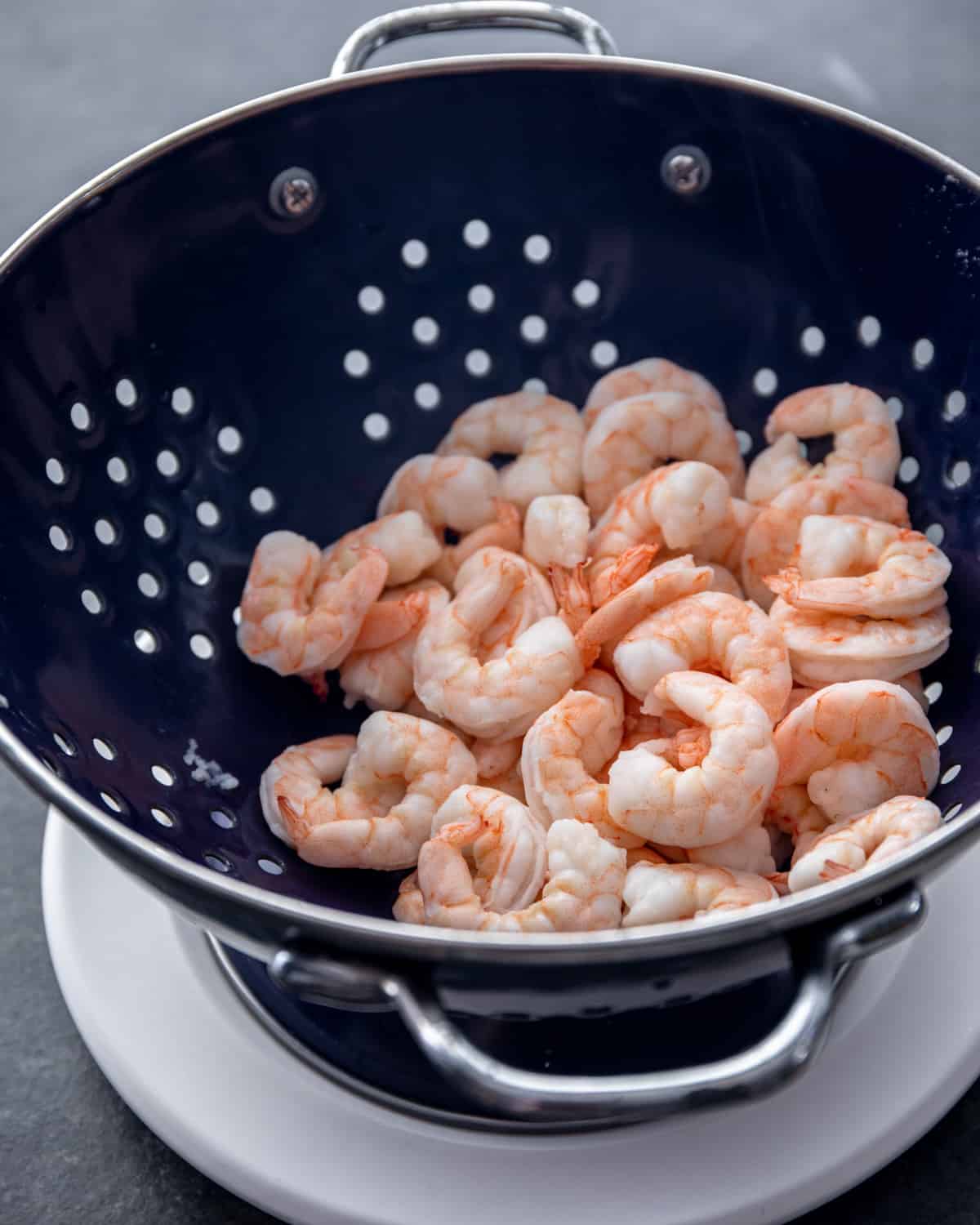 rinsing shrimp in a black colander