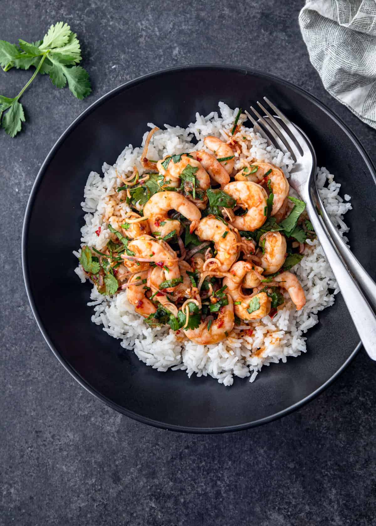 overhead image of shrimp salad over rice in a black bowl