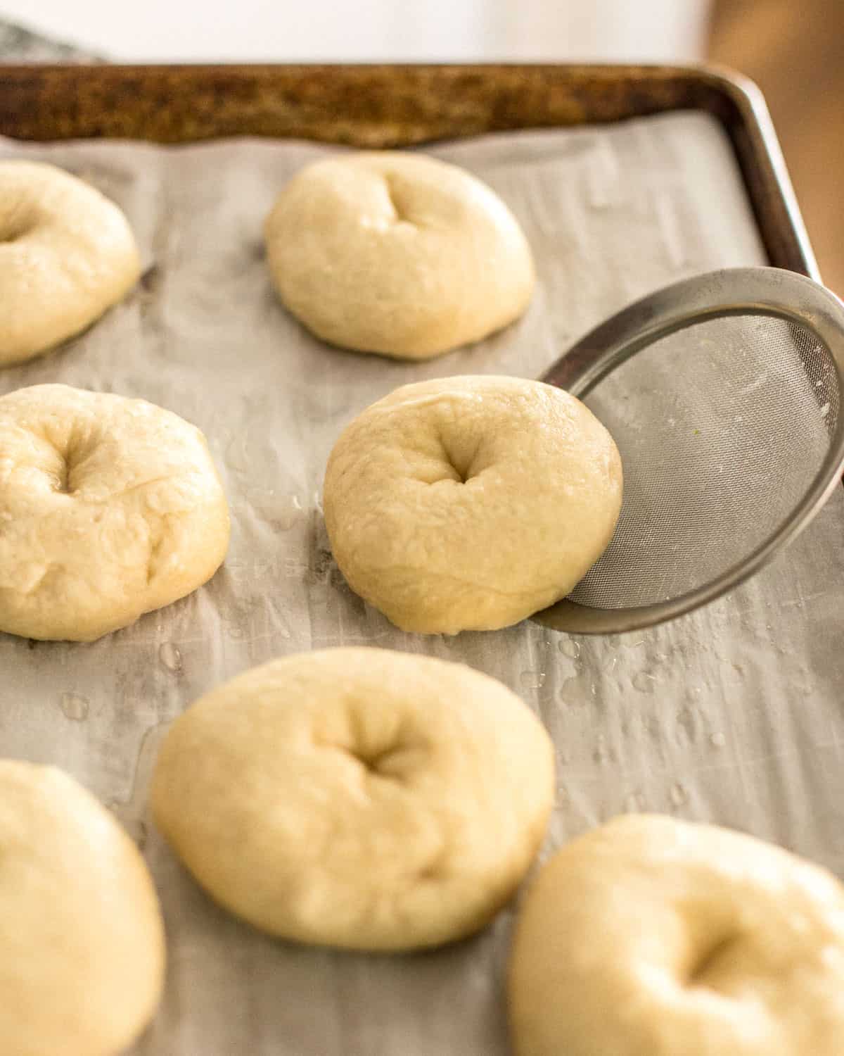 placing boiled bagels on a parchment lined sheet pan