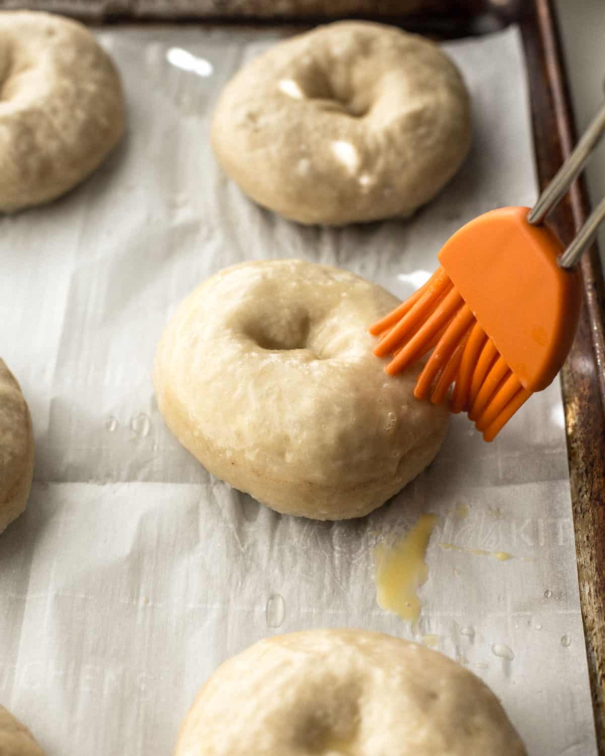 brushing tops of bagels with butter