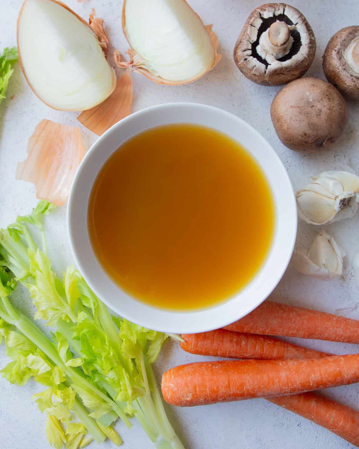 IMG_1145 overhead image of vegetable broth in a small white bowl, surrounded by raw vegetables