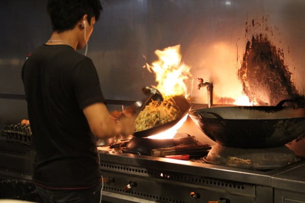 a chef cooking pad thai in a wok