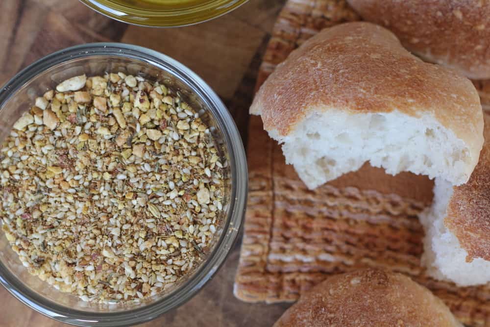 dukkah spice in a clear glass jar next to a piece of roll