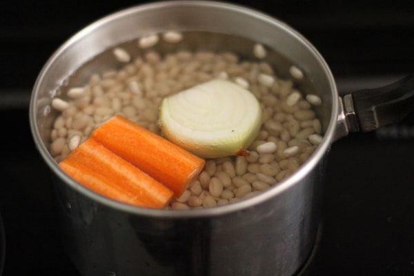 cooking white beans in a pot with carrots and onion 