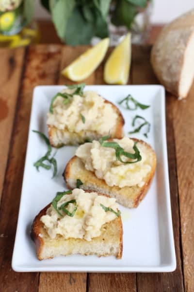 white bean bruschetta on a white rectangular platter 