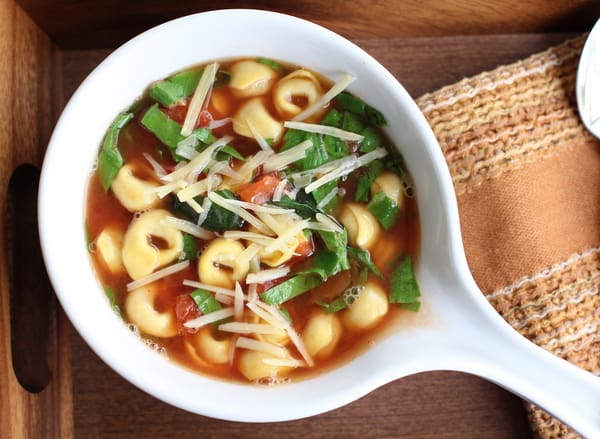 Tortellini, Basil, and Fire Roasted Tomato Soup in a small white bowl with a handle