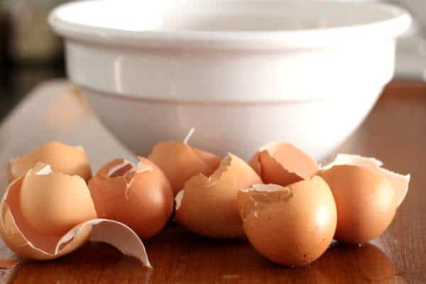 egg shells and a white bowl on a wooden table