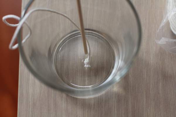 overhead image showing adding a wick to a clear jar