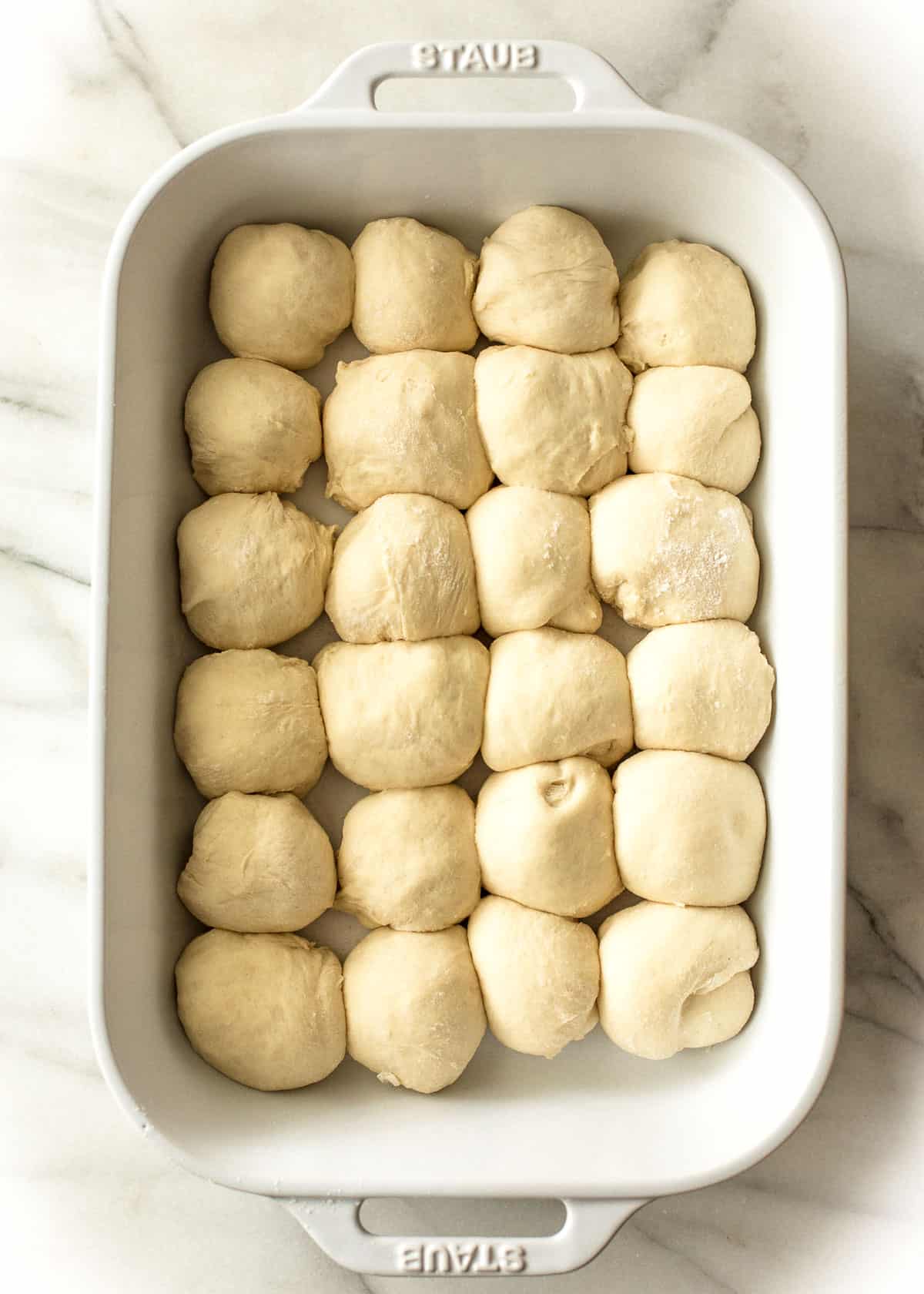 overhead image of unbaked rolls in a baking pan