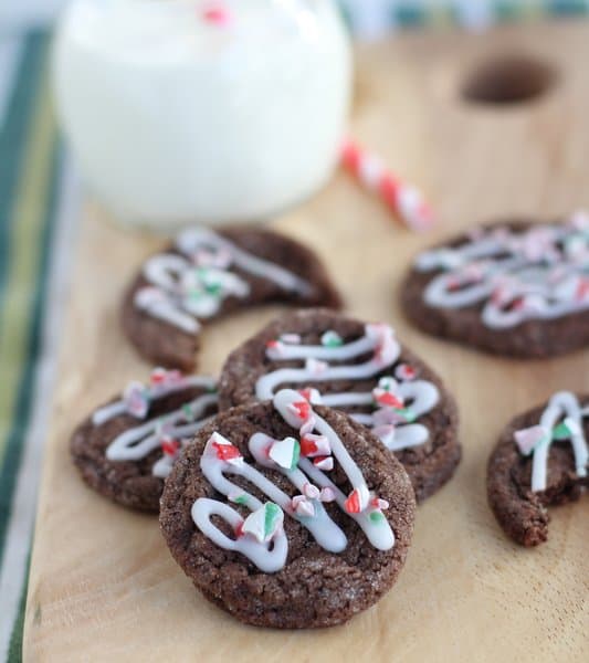 chocolate cookies topped with candy cane topping on a wooden tray