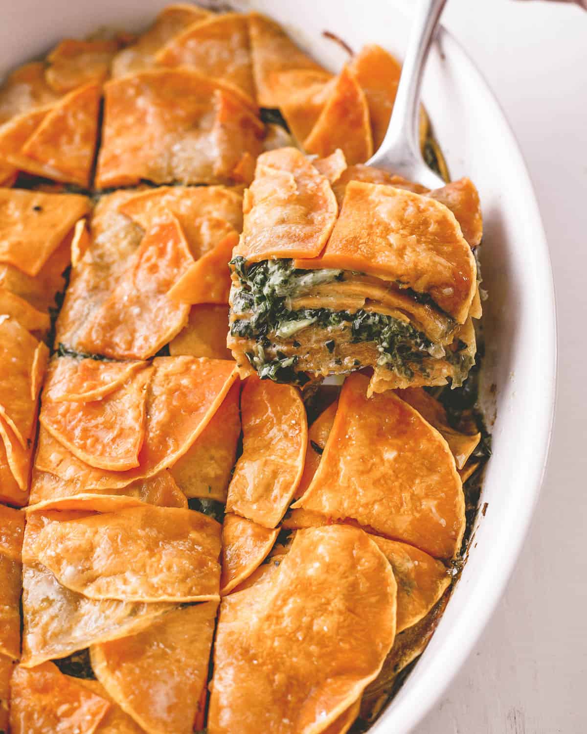 removing a piece of squash and spinach casserole with a spatula