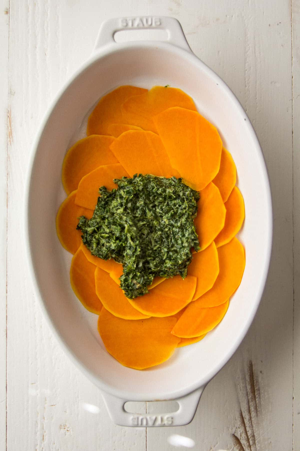 overhead image of squash slices and spinach mixture in an oval baking dish