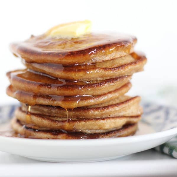 a stack of pancakes topped with butter and syrup on a blue and white plate