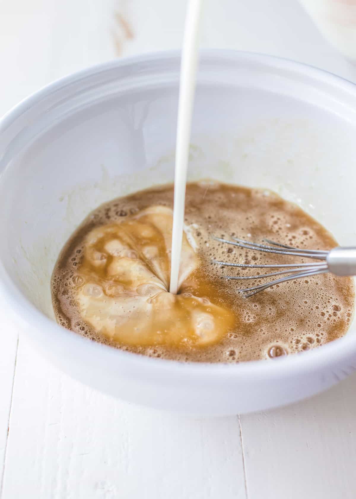 adding buttermilk to bowl of pancake ingredients