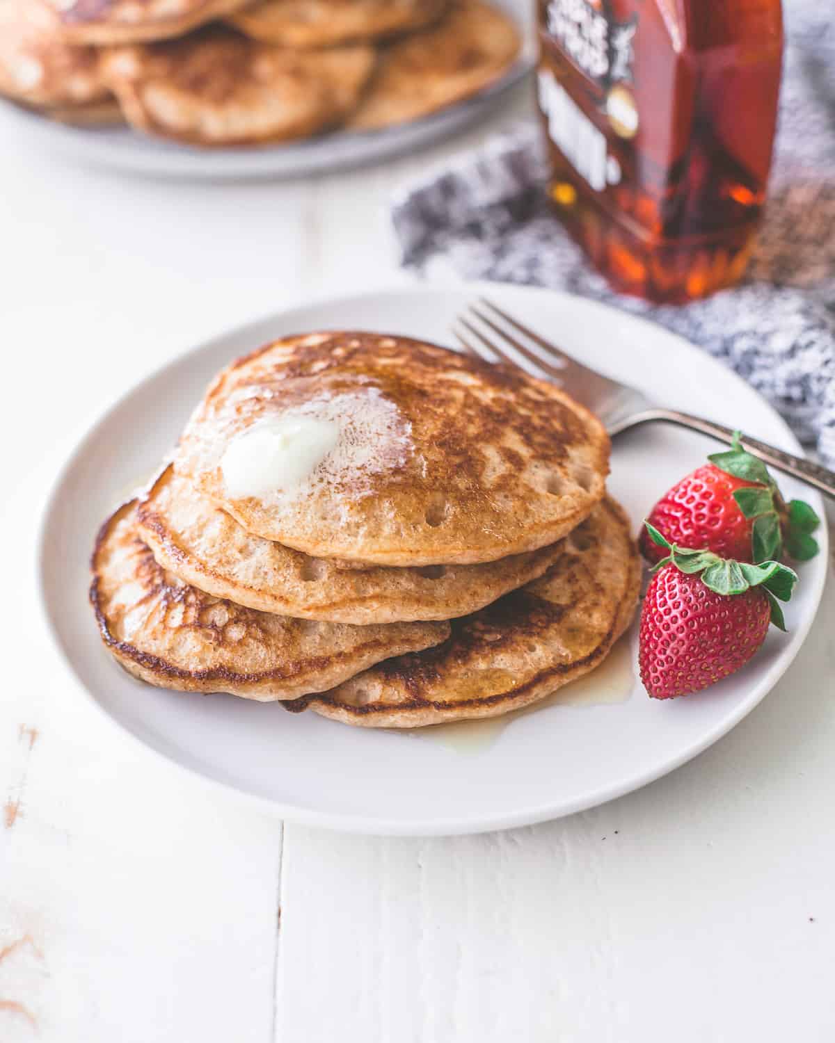whole wheat pancakes on a white plate with a fork