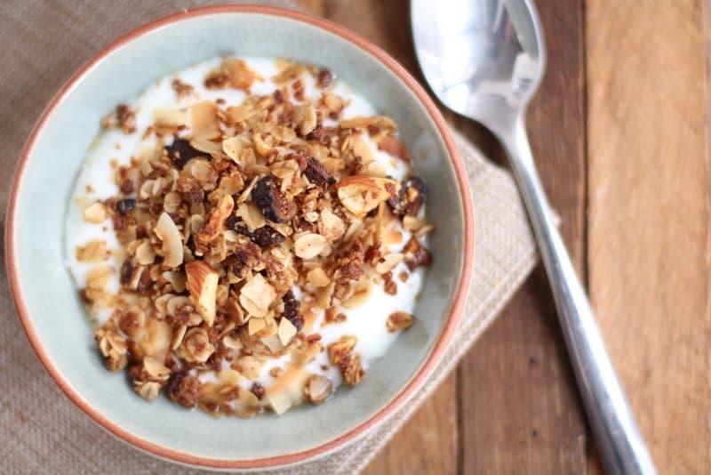 granola topping yogurt in a blue bowl with a spoon