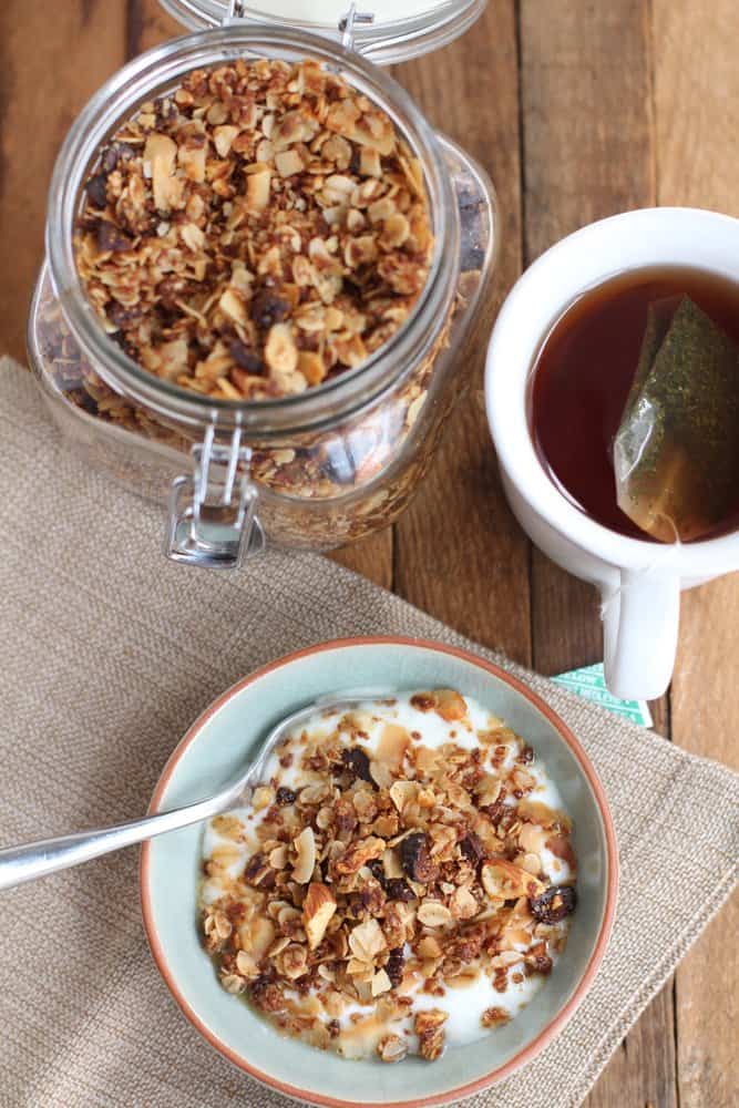 granola in a glass jar, and topping yogurt in a blue bowl