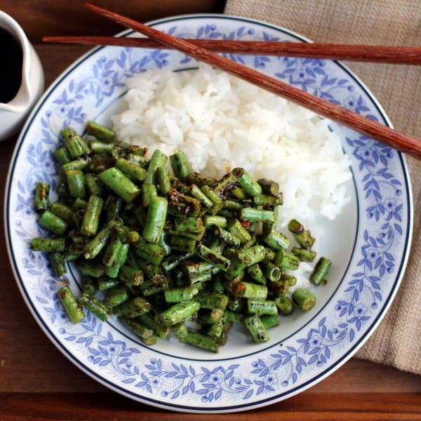 spicy green beans and rice on a blue and white plate