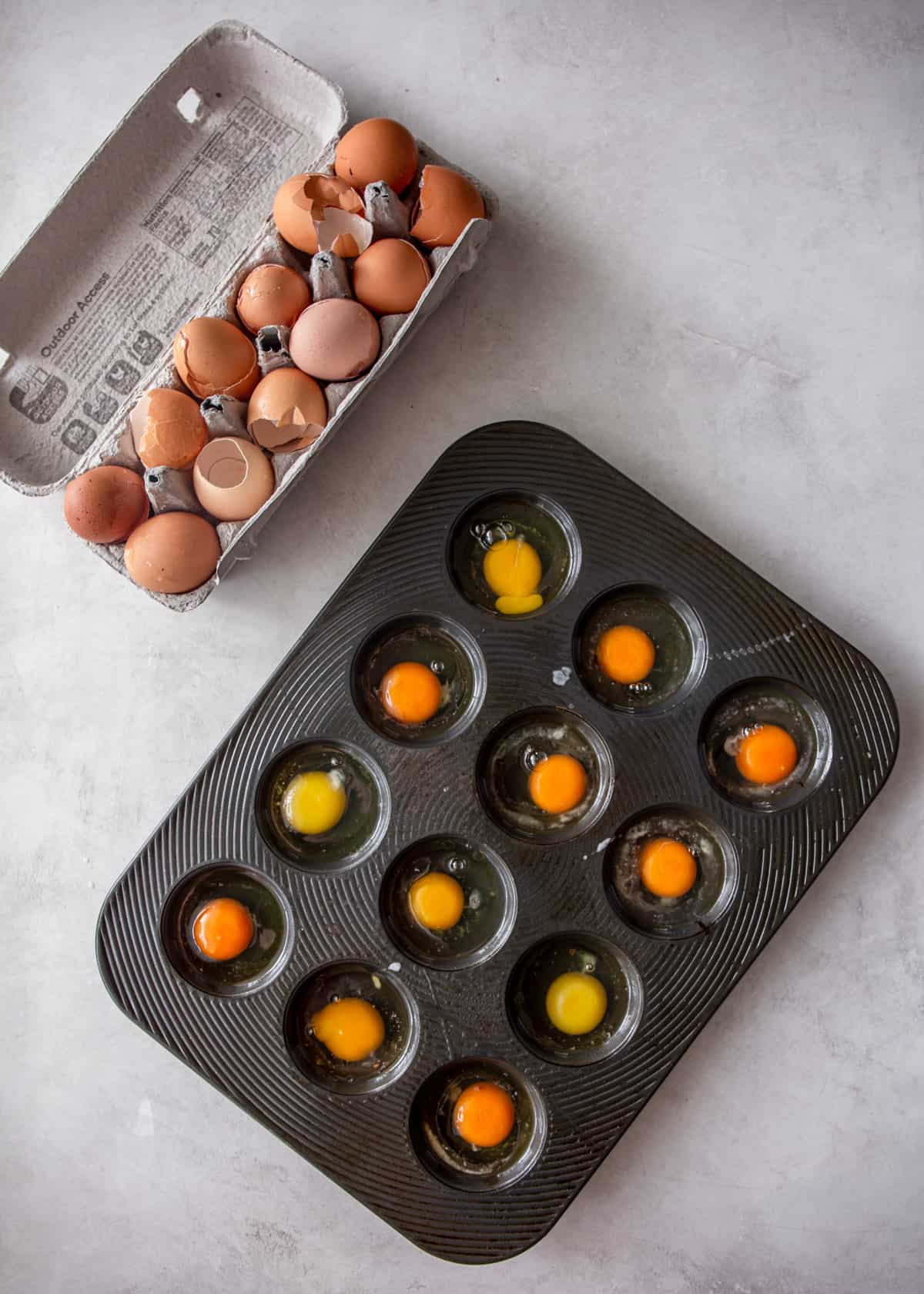 overhead image of 12 eggs cracked into a muffin pan