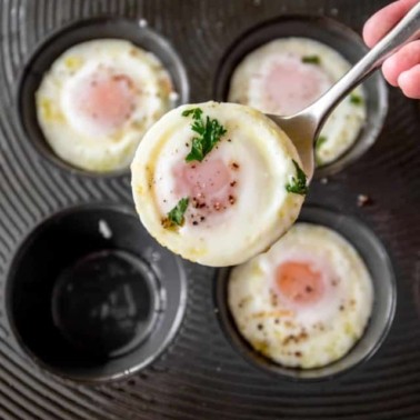 overhead image of a baked egg being removed from a muffin pan