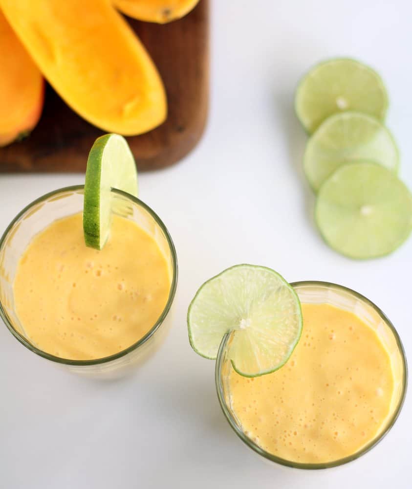 mango drink in clear glasses with lime wedges on the rim