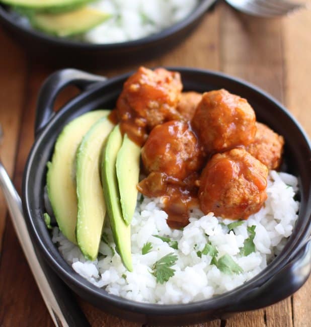 meatballs, rice and avocado slices in a black bowl
