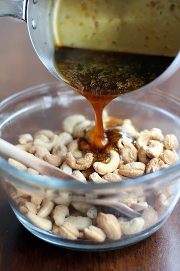 adding spicy sauce to cashews