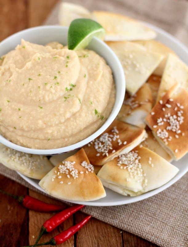 bean dip in a white bowl with pita chips on a white plate