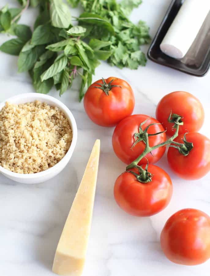 cheese, herbs, quinoa and tomatoes on a white countertop