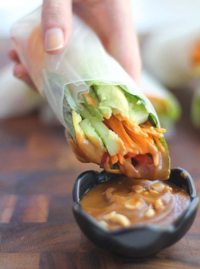 dipping a summer roll in to peanut sauce