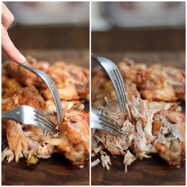 pulling chicken with two forks on a wooden cutting board