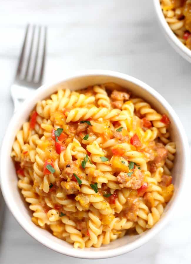 pasta in a white bowl on a marble countertop with a fork