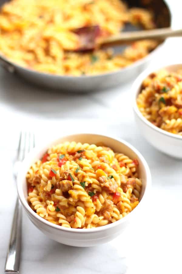 pasta with vegetables in white bowls on a marble countertop