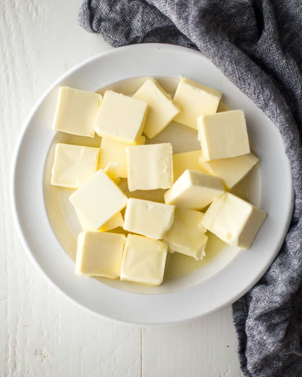 overhead image of slices of unsalted butter on a white plate