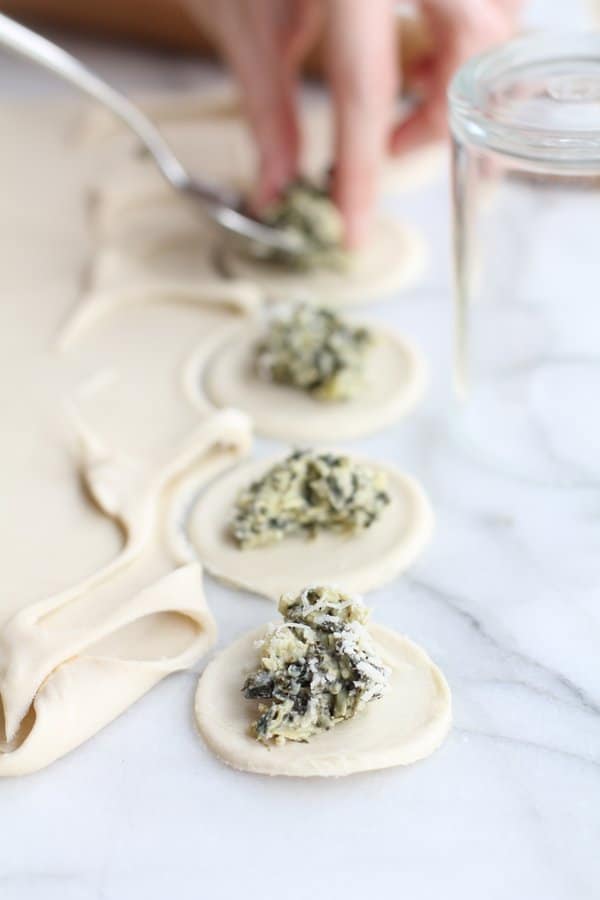 putting spinach filling in the center of puff pastry discs