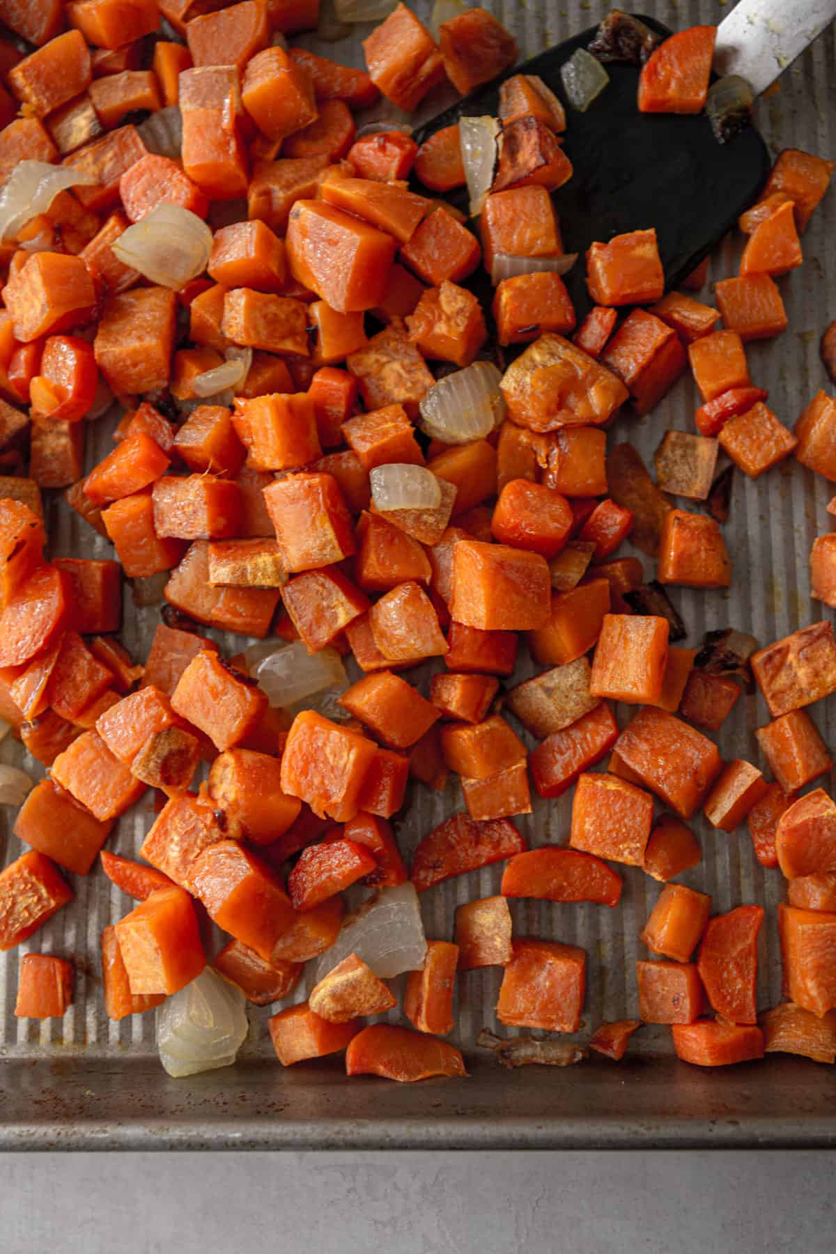 roasted sweet potatoes, carrots, and onions on a sheet pan