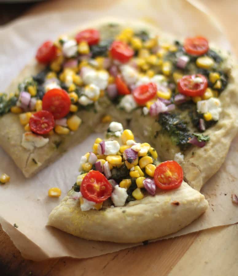 summer pizza, cut into slices on a sheet of parchment paper