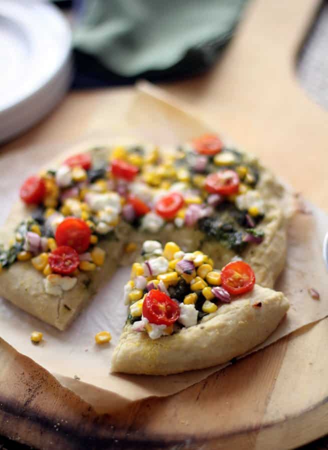 a slice of homemade pesto pizza on a sheet of parchment paper