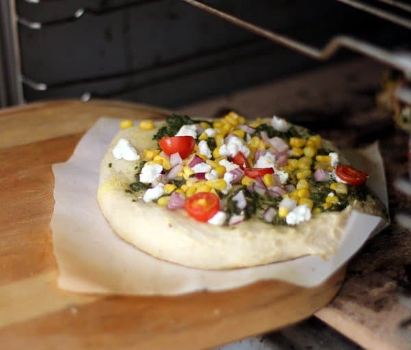 a homemade sweet corn pizza coming out of the oven