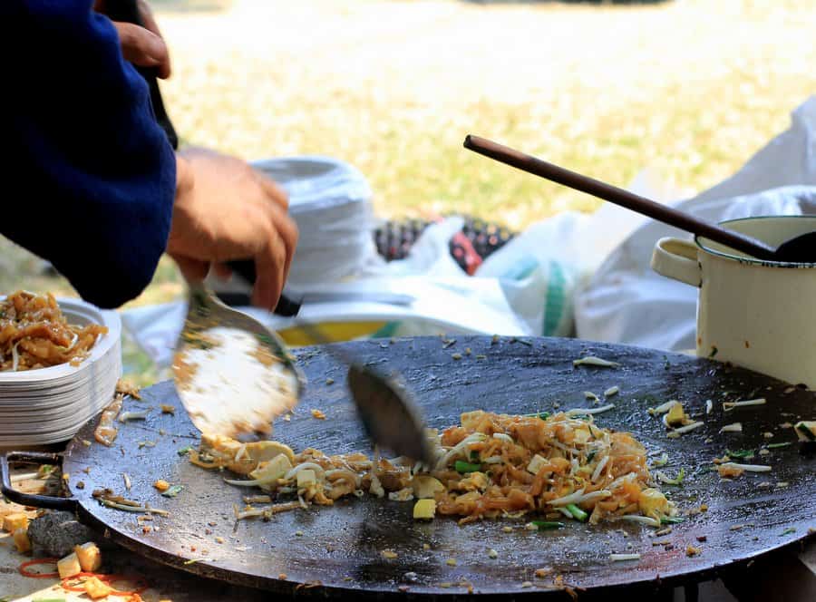 a chef cooking pad thai on a large wok