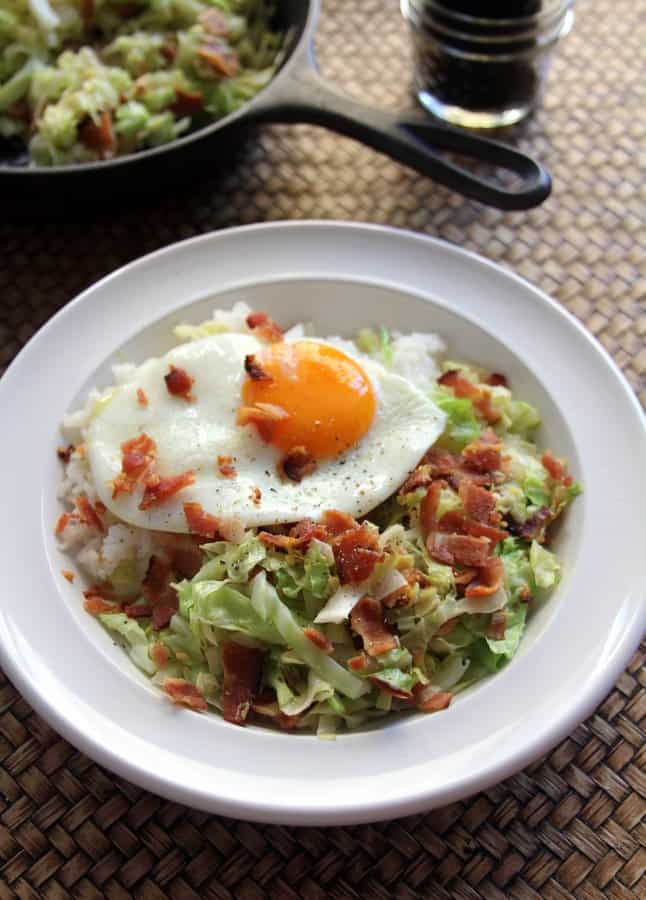 cabbage and bacon in a white bowl, topped with a fried egg
