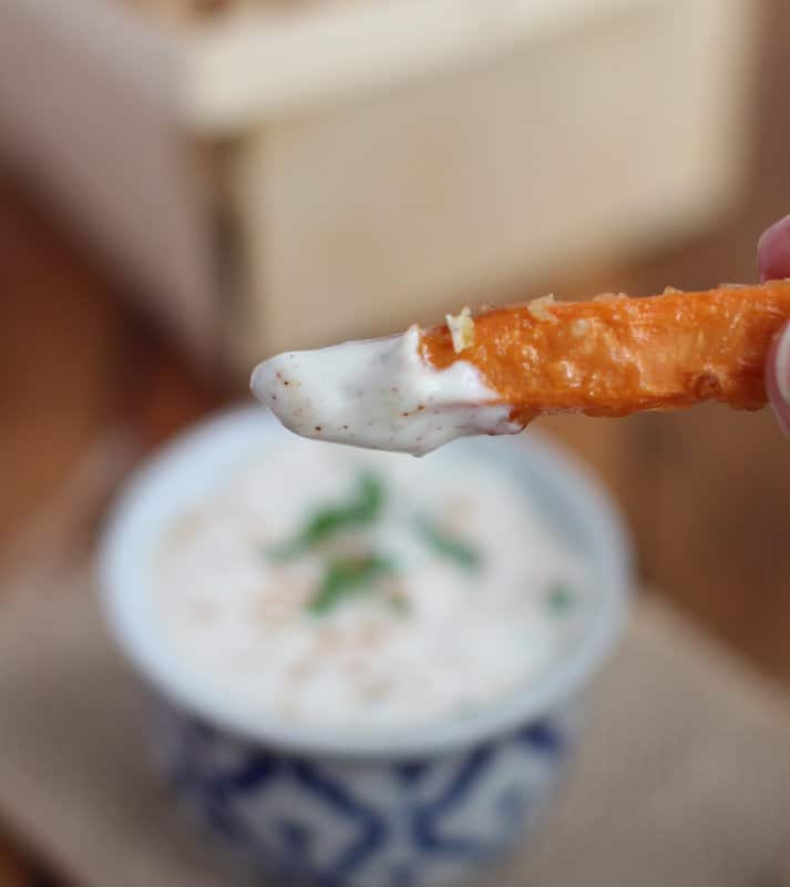 a fry dipped in yogurt dipping sauce